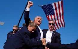 Trump first ducked behind the lectern as security staff shielded him before eventually standing up again with a clenched fist as he headed out of the premises